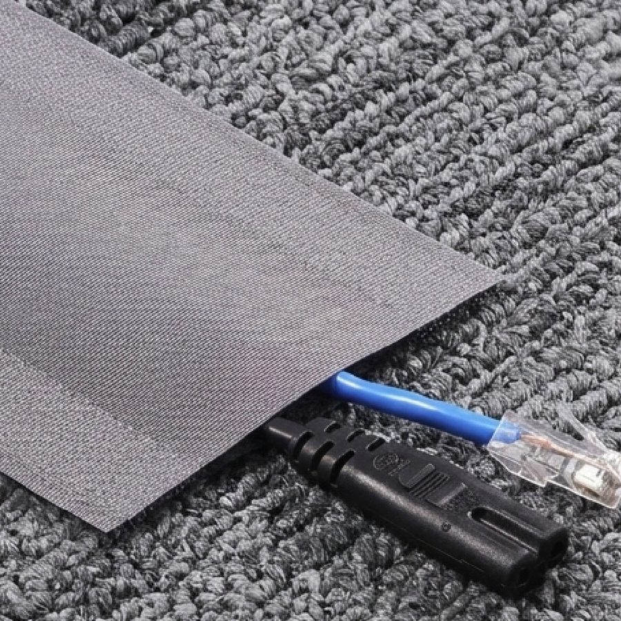 A grey cord cover hiding cables on a carpet